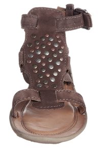 Bruna lädersandaler har flera remmar och metallnitar på ovandelen. Sulan är slät, med en platt design för komfort.