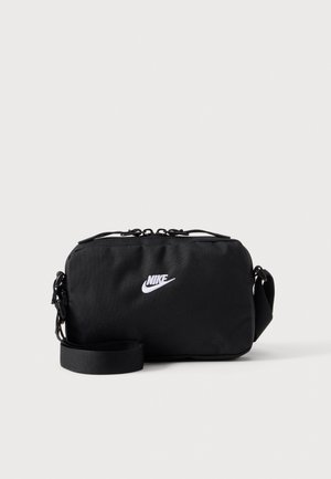 Черна чанта за рамо Nike с бяло лого, цип и регулируема презрамка, показана на изчистен светъл фон.