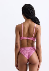 Roze kanten lingerieset met bloemenpatronen, verstelbare bandjes en een bijpassende string met fijne details aan de randen.