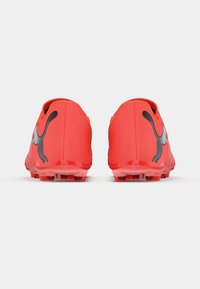 Tacos de fútbol rojos con una superficie texturizada, que presentan un logo negro y un soporte suave para el talón, diseñados para tracción en superficies de césped.