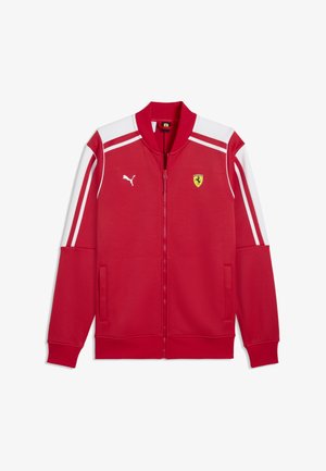 Chaqueta roja con cremallera, con rayas blancas en las mangas, logo de Puma en el lado izquierdo del pecho y emblema del escudo de Ferrari en el lado derecho del pecho.
