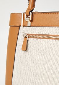 Borsa a tracolla in pelle color testa di moro con corpo in tessuto crema testurizzato, dotata di una zip in tono oro e una tasca laterale con un'etichetta in pelle.