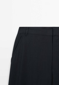 Pantalon noir à texture lisse, doté d'une ceinture, de poches latérales et de jambes à coupe droite. Design minimaliste sans motifs visibles.
