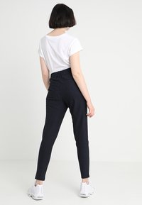 Högmidjade marinblå rutiga byxor med en figurnära silhuett, stretchigt material och två bakfickor, i kombination med en vit kortärmad skjorta.