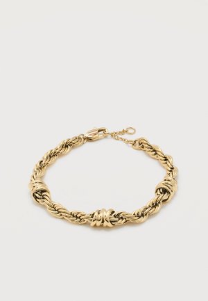 Χρυσό πλεγμένο βραχιόλι με τρεις γυαλιστερές στριφογυριστές κρίκους και κούμπωμα καβουριού σε λευκό φόντο.