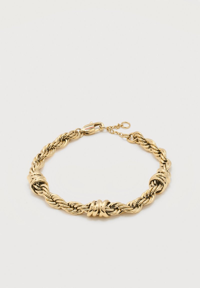 Χρυσό πλεγμένο βραχιόλι με τρεις γυαλιστερές στριφογυριστές κρίκους και κούμπωμα καβουριού σε λευκό φόντο.