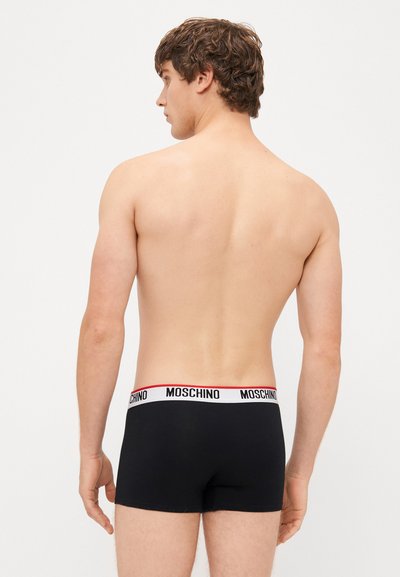 Fekete pamut boxer alsónemű fehér derékkal, piros díszcsíkokkal és fekete "MOSCHINO" logóval. A modell hátsó nézete.