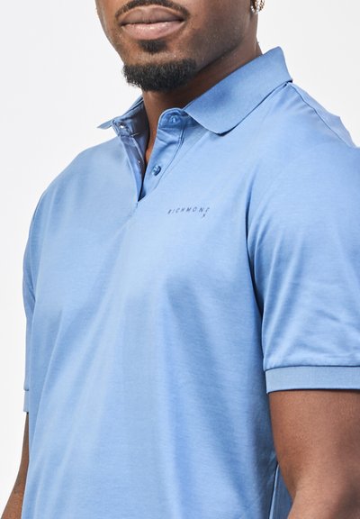 Polo shirt azzurro chiaro in tessuto morbido, con colletto, maniche corte e un logo ricamato discreto sul petto.