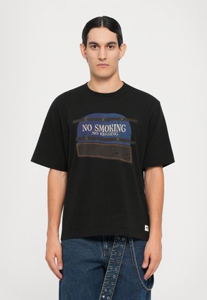 Black cotton t-shirt featuring a graphic print with "NO SMOKING NO KISSING" in blue and brown. Loose fit, short sleeves, and crew neckline.