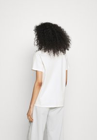 White cotton t-shirt with a classic cut, short sleeves, and a rounded neckline. Smooth texture, simple design, and minimalistic style.