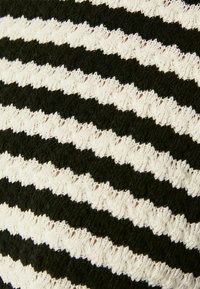 Tissu rayé noir et blanc présentant un motif en zigzag avec des sections alternant entre lisses et texturées. Matière douce et tricotée.
