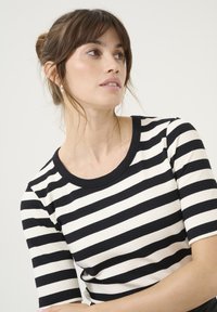 Must-valged, ribakootud pika käisega top, millel on ümar kaelus ja lühikesed varrukad. Sile tekstuur, kitsenev disain ja kontrastsed triibud.