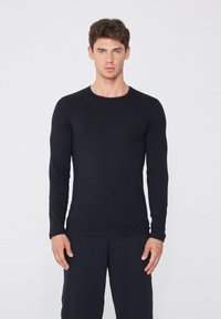 Schwarzes Langarmshirt aus glattem Stoff, mit rundem Ausschnitt und tailliertem Schnitt. Schlichter Stil ohne sichtbare Muster oder Verzierungen.