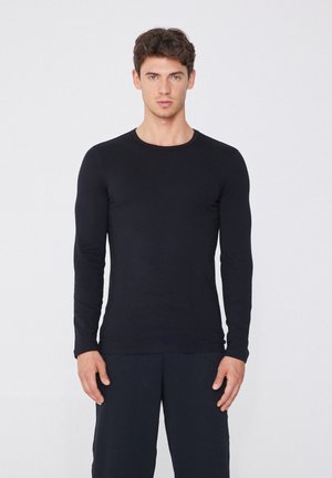 Camisa negra de manga larga hecha de tela suave, con cuello redondo y un diseño ajustado. Estilo simple sin patrones ni ornamentaciones visibles.