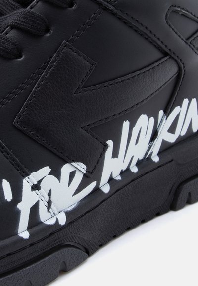 Μαύρο δερμάτινο αθλητικό παπούτσι με μεγάλο ανάγλυφο λογότυπο 'K', λευκό χειρόγραφο κείμενο και υφασμένο λαστιχένιο πέλμα με έντονο σκαλίδωμα.