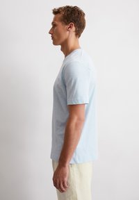Hellblaues T-Shirt mit kurzen Ärmeln aus weichem Baumwollstoff. Verfügt über einen runden Halsausschnitt und einen lässigen Schnitt, mit einer einfachen, glatten Textur.