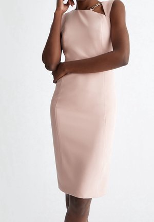 Hellrosa tailliertes Kleid aus glattem Stoff, mit quadratischem Ausschnitt und einer Kettenverzierung auf einer Schulter. Länge bis zur Mitte des Oberschenkels.