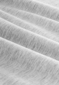 Lys grå stof med en blød, tekstureret overflade og subtile mønstre samt bløde folder, hvilket indikerer et let og åndbart materiale.