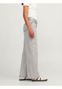 Ljusgrå vida jeans i denim, med hög midja, bältesloopar och klassisk femficksdesign. Stylad med en vit t-shirt och sneakers.