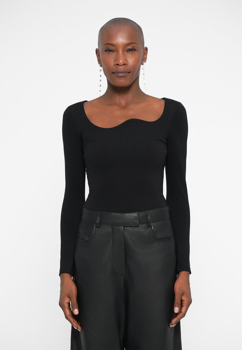 Bodysuit negro de manga larga con un escote curvado, combinado con pantalones de cuero negro de cintura alta. Material suave con un diseño ajustado.