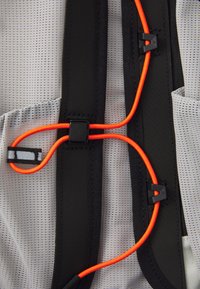 Lightweight gray mesh fabric with black straps. Features orange elastic cord with black hardware, enabling adjustable fit and secure closure.