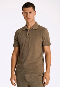 Mörkbrun kortärmad polo med en mjuk textur, treknappars placket och klassisk krage. Enhetligt tyg utan synliga mönster.