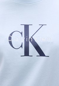 Ανοιχτό μπλε φούτερ με μεγάλο σκούρο ναυτικό λογότυπο "CK" και κεντημένο γράψιμο "CalvinKlein" από κάτω. Ομαλή υφή βαμβακιού.