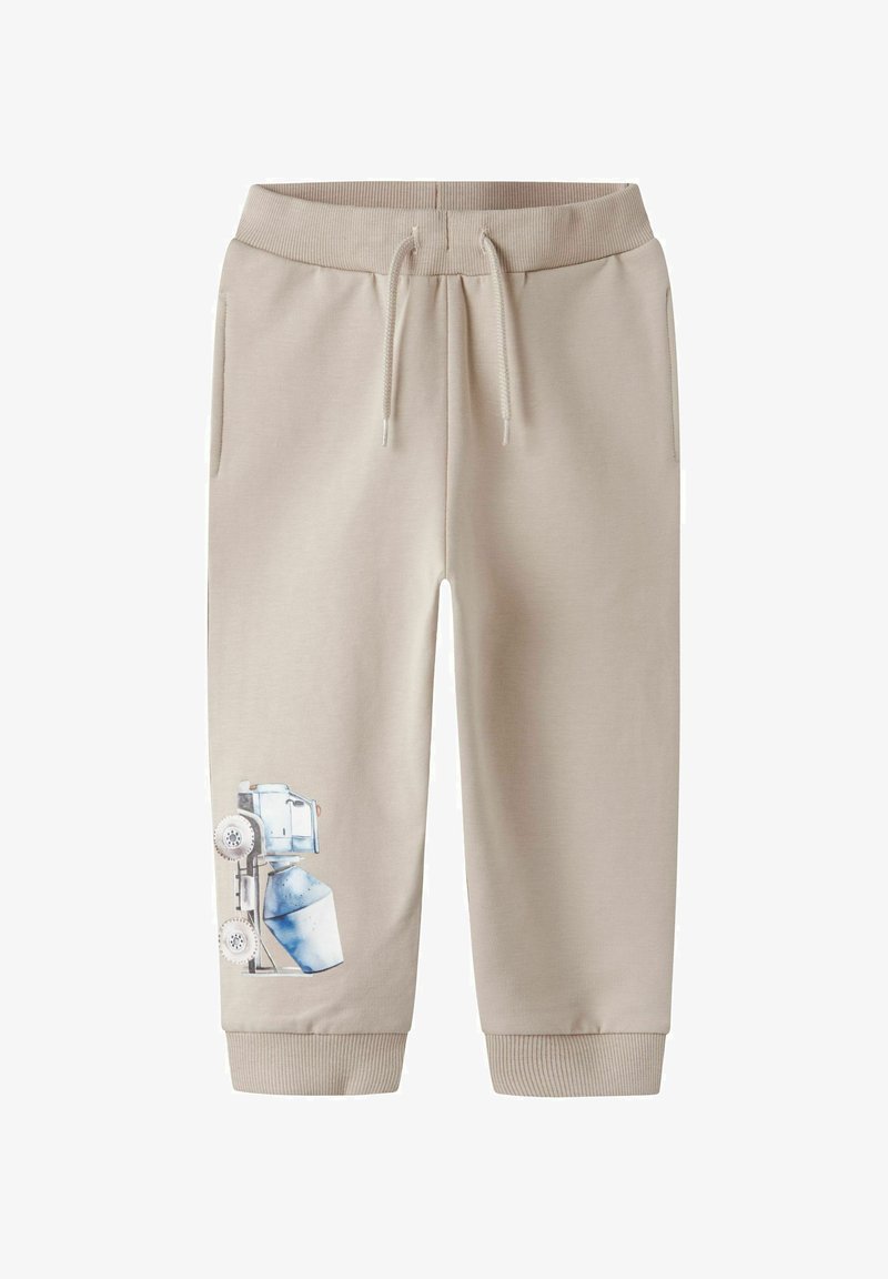 Beige Sweatpants mit einem Kordelzugbund, gerippten Bündchen und einem bedruckten Design eines blauen Spielzeuglastwagens am linken Bein. Aus weichem Baumwollmaterial.