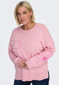 Suéter rosa tejido con diseño floral en las mangas, dobladillo y puños acanalados. La tela parece suave y de un ajuste relajado.