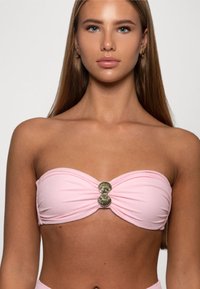 Roze bandeau bikini-top met een gedraaide ontwerp, voorzien van een schelpvormige metallic accent in het midden. Gladde textuur, eenvoudige stijl.