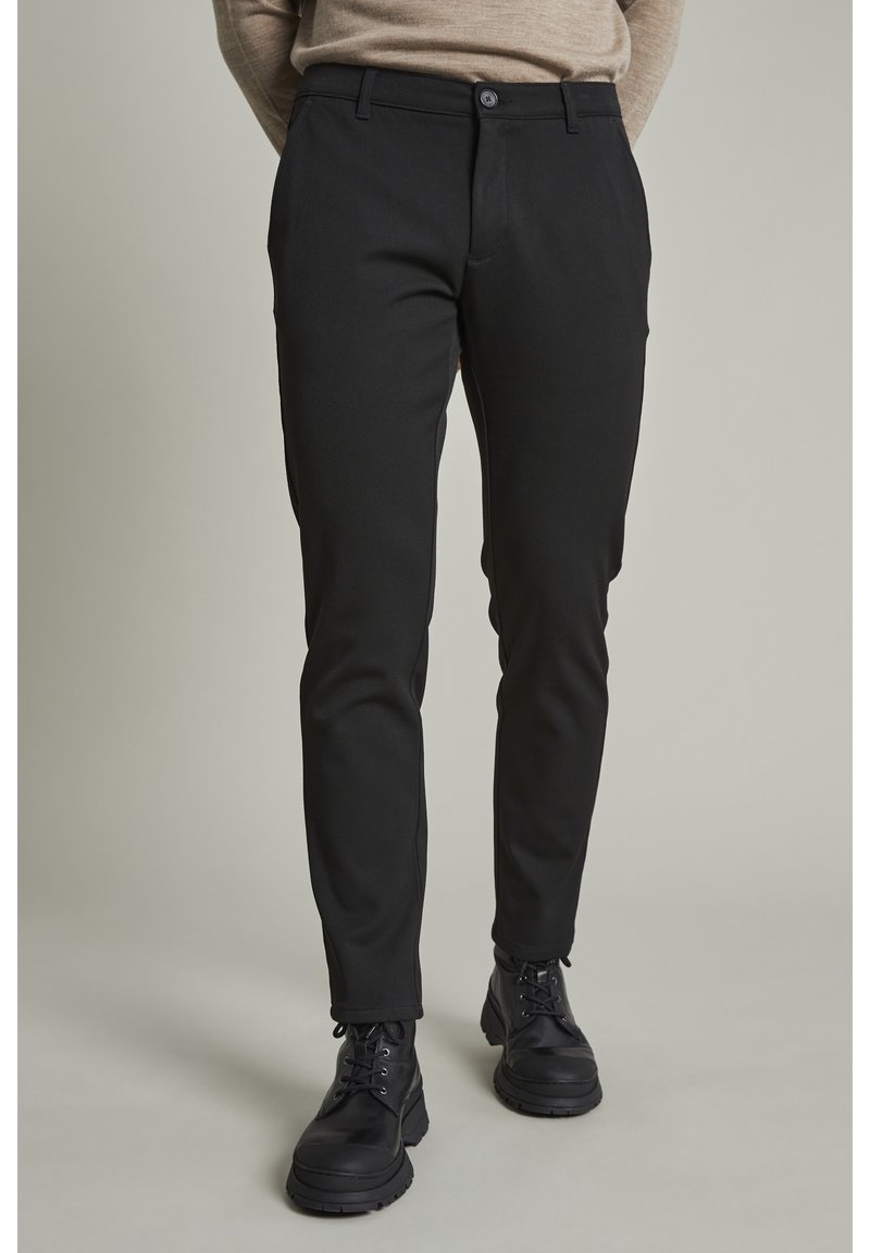 Svarta byxor med slim fit, med knappstängning och sidofickor. Tillverkade av ett mjukt, stretchigt tyg för komfort.