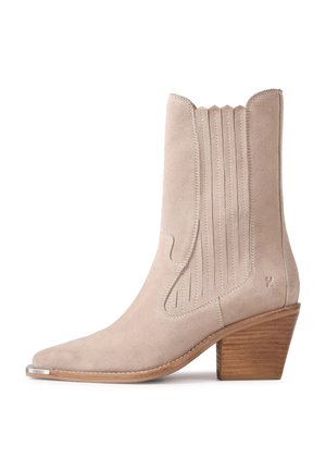 Beige suède cowboylaars tot halverwege de kuit met gestapelde houten hak, gestikte zijpanelen, puntige neus en klein metalen voorschoendopje.