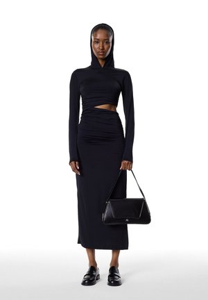Black long-sleeve dress with hood, featuring gathered detailing and a midriff cutout. Paired with a black structured handbag and loafers.