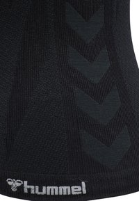 Zwart atletisch kledingstuk met een gestructureerd patroon en een verhoogd chevronontwerp. Bevat een wit "hummel" logo aan de onderrand.
