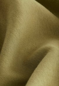 Tejido de color verde oliva con una superficie suave y texturizada. El material parece tejido, mostrando un patrón sutil y una caída delicada.