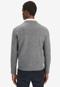 Grijze gebreide trui met een V-hals, geribbelde boorden en zoom, met een zachte textuur en een casual pasvorm, gedragen over een witte blouse met kraag.