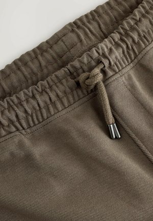 Braune, strukturierte Hosen mit einem elastischen Bund, ausgestattet mit einem Kordelzug mit Metallspitzen und Ziernähten entlang der Kanten.