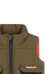 Gilet rembourré en vert olive avec col haut, fermeture éclair marine et accents orange aux épaules. Comprend deux poches avant avec le logo Timberland.