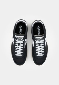 Black athletic shoes with white accents, featuring a lace-up design, rubber sole, and logo on the tongue and side.