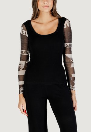 Black long-sleeve top features a ribbed texture with sheer printed sleeves showcasing graphic patterns in shades of brown and cream.