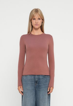 Long-sleeve, fitted top in dusty rose, made of smooth cotton fabric. Crew neckline, minimal seams, paired with light blue wide-leg jeans.