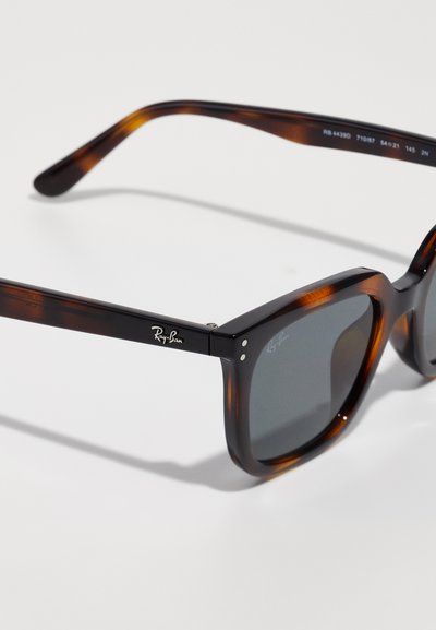 Слънчеви очила Ray-Ban в черупка на костенурка с тъмни квадратни стъкла, видимо лого на рамката и стъклото, показани на бял фон.