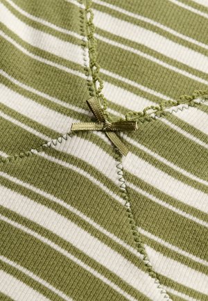 Tissu côtelé rayé vert et blanc avec une couture décorative verte et un petit nœud en satin vert à la jonction des coutures.
