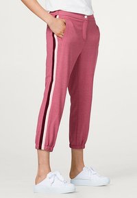 Roze tapered joggerpants met witte zijkanten, elastische boorden en steekzakken, gemaakt van een zachte, gestructureerde stof.