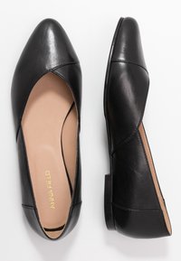 Ballerine in pelle nera con punta appuntita, design a ritaglio e tacco minimo. L'interno presenta una fodera beige. Nome del marchio visibile all'interno.
