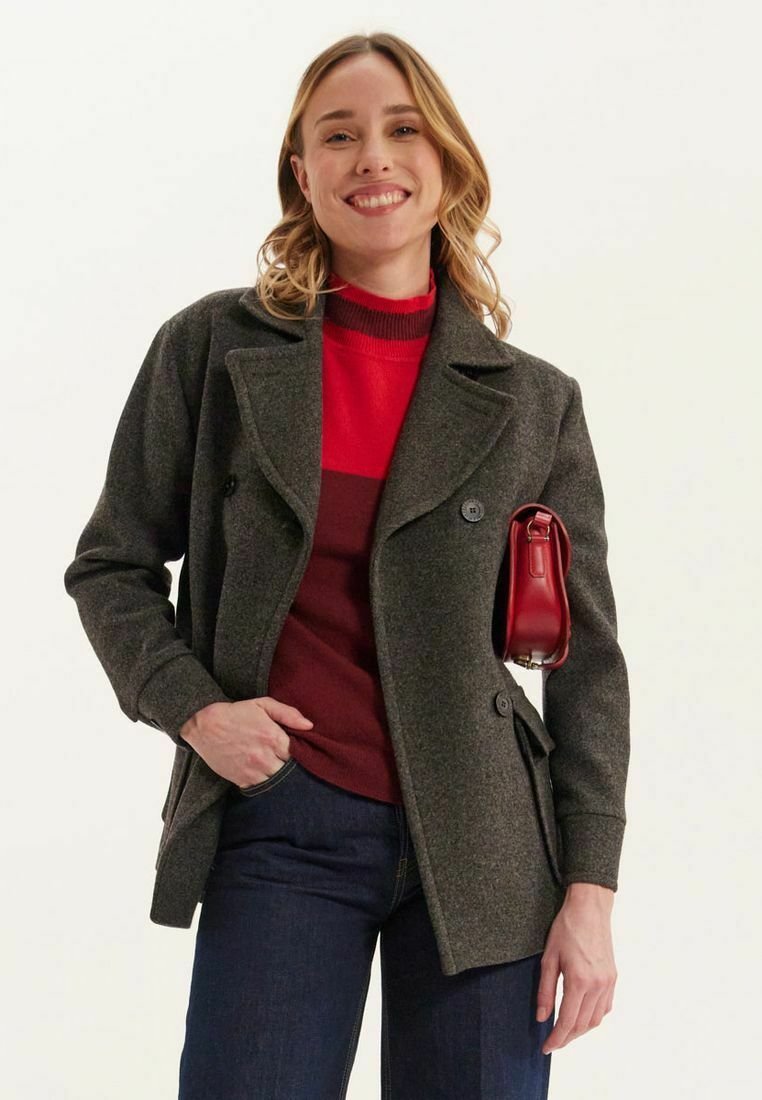 Manteau peacoat en mélange de laine gris avec des boutons double boutonnage, porté sur un pull rayé rouge, associé à un jean noir et un petit sac à main rouge.