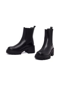 Bottes noires en cuir jusqu'à la cheville avec un bout rond, des panneaux latéraux élastiques et une semelle en caoutchouc épaisse avec des rainures profondes pour une meilleure adhérence.