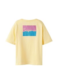 Żółta koszulka z krótkim rękawem z kolorową kwadratową grafiką z tyłu, na której widnieje słowo "California" w białym, stylizowanym piśmie.