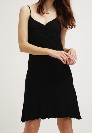 Sort ærmeløs kjole med en samlet buste, glat tekstur og en udvidet kant med en bølget kantdetalje.