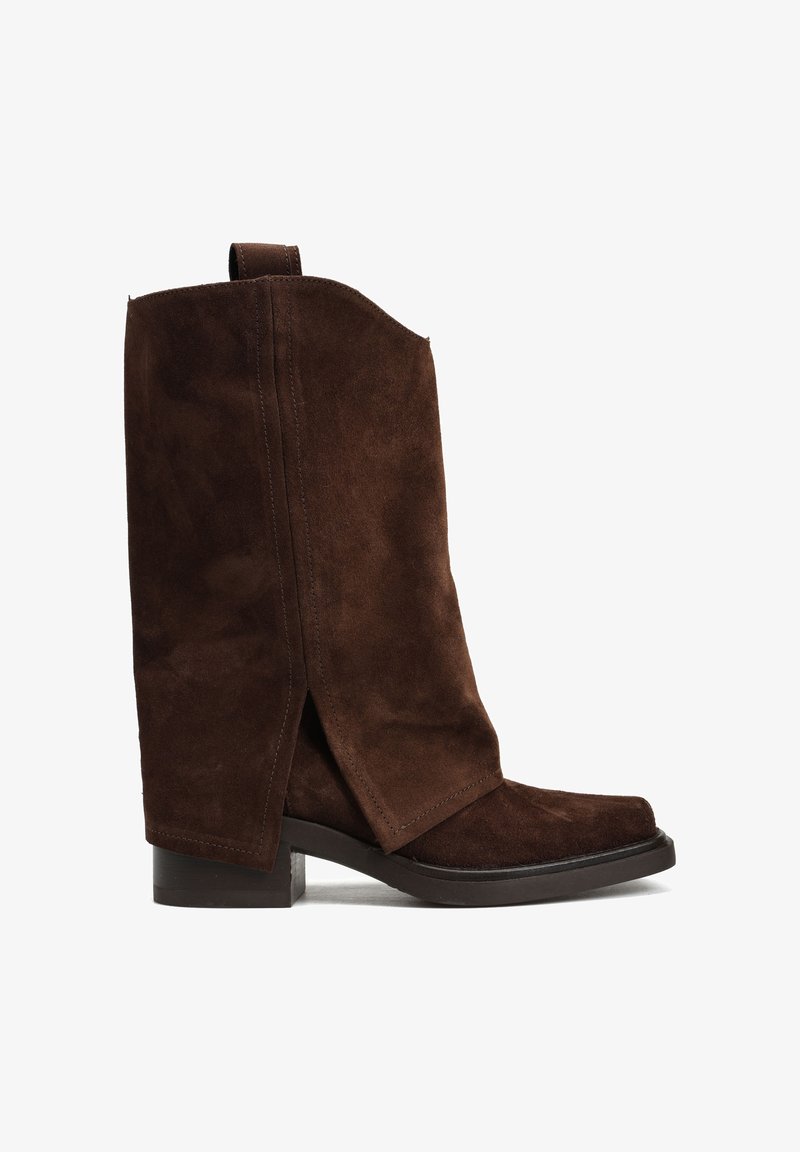 Brązowy zamszowy botek za kostkę o luźnym fasonie, kwadratowym nosku i podwyższeniu w formie słupka. Widoczny szew boczny, miękka tekstura i brak widocznych elementów metalowych.